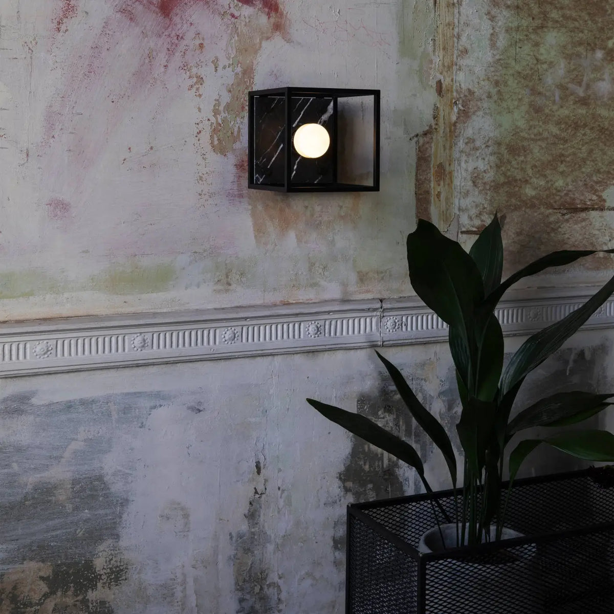 Applique murale cage en acier noir mat sur fond de marbre poli