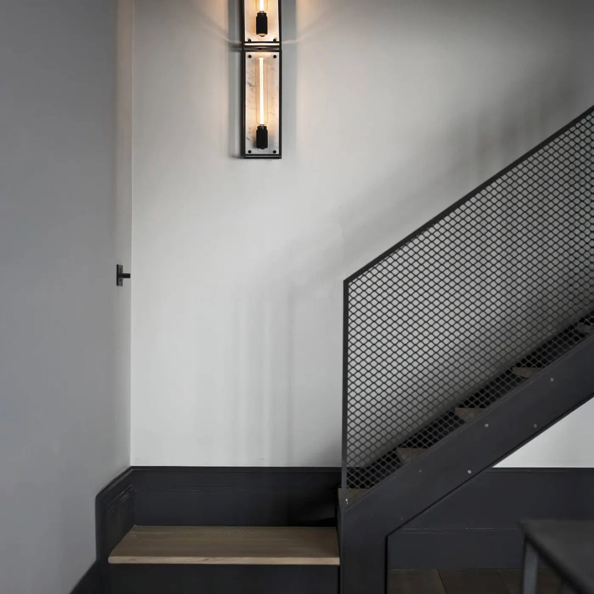 Applique murale cage en acier noir mat sur fond de marbre poli