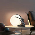 Lampe sculpture, silhouette enlaçant une sphère lumineuse, noir