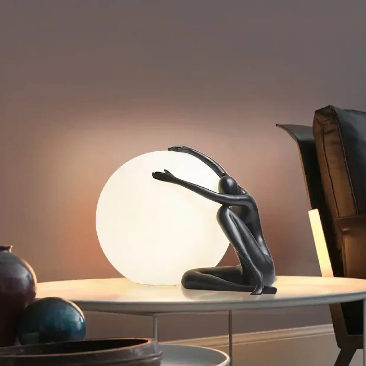 Lampe sculpture, silhouette enlaçant une sphère lumineuse, noir