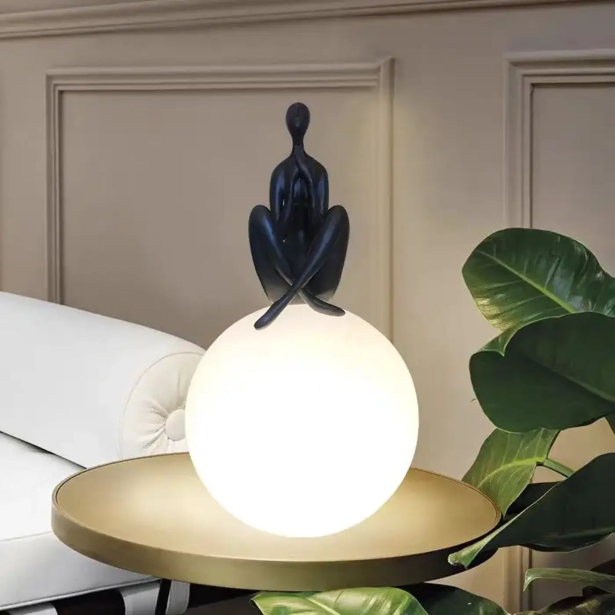 Lampe sculpture, silhouette enlaçant une sphère lumineuse, noir